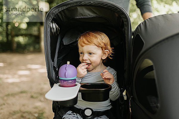 Kleinkind beim Essen im Kinderwagen