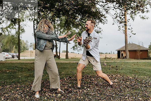 Junger Mann wirft auf dem Land spielerisch Blätter auf Frau