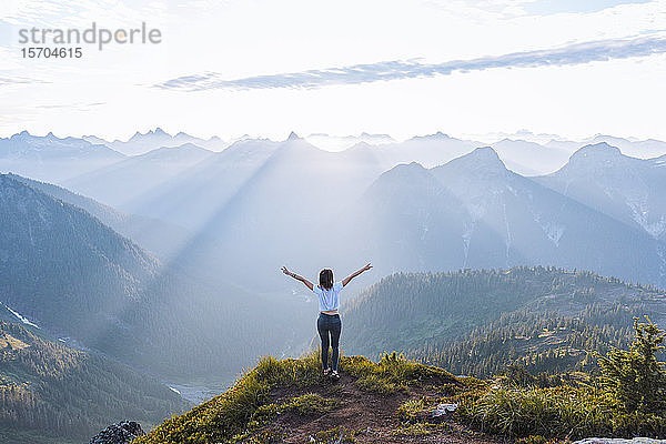 Wanderin  die auf dem Gipfel die Arme gegen die Sonne hebt  Winchester Mountain  North Cascades  Washington  USA