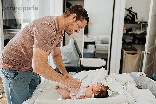 Vater wechselt die Windel eines kleinen Mädchens auf dem Wickeltisch