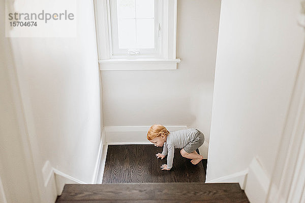 Kleinkind krabbelt im Haus die Treppe hoch