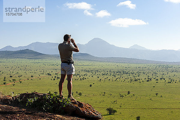 Ranger mit Blick von der Hügelspitze  Lualenyi-Wildreservat  in der Nähe des Tsavo-Ost-Nationalparks  Kenia