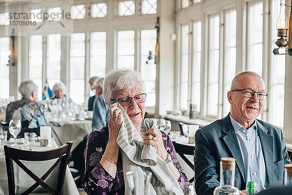 Ältere Frau weint  während ein männlicher Freund im Restaurant lächelt