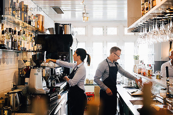 Männliche und weibliche Mitarbeiter  die in der Küche eines Restaurants arbeiten