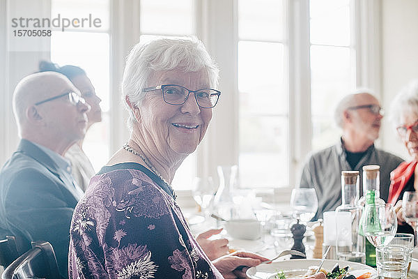 Porträt einer älteren Frau  die lächelnd neben Freunden im Restaurant sitzt