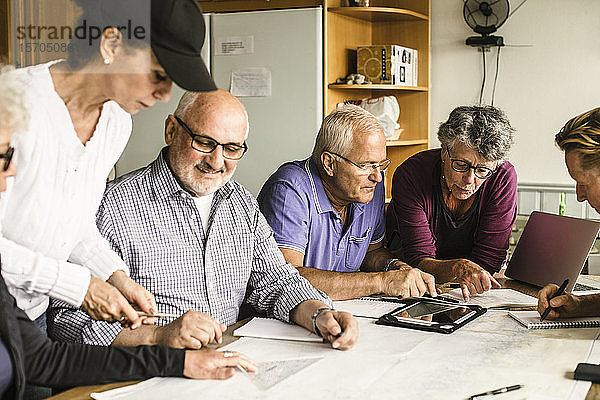 Ältere Männer und Frauen diskutieren am Tisch während des Navigationskurses