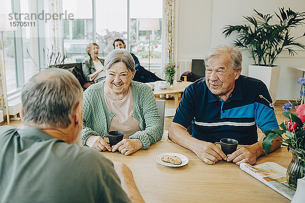 Ältere ältere Freunde unterhalten sich am Esstisch im Pflegeheim