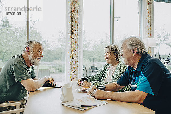 Seniorenfreunde im Ruhestand beim Gespräch am Esstisch im Pflegeheim