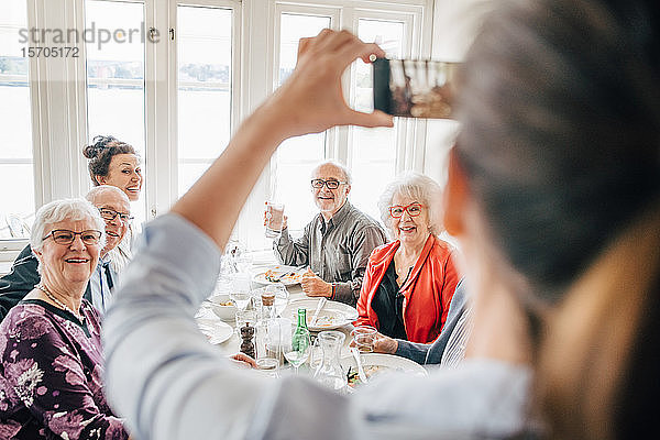 Eigentümer klickt auf Foto von älteren Freunden  die im Restaurant sitzen