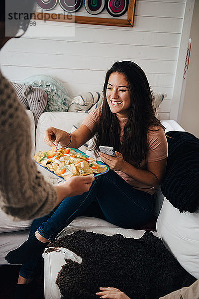 Ausgeschnittenes Bild eines Freundes  der einer lächelnden Frau zu Hause Snacks serviert