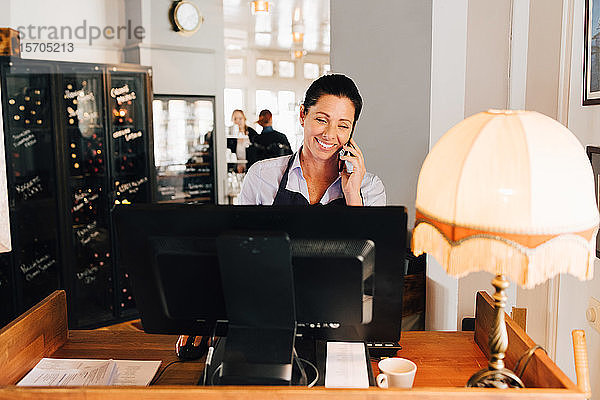 Lächelnde Frau nimmt im Restaurant per Handy Bestellungen entgegen