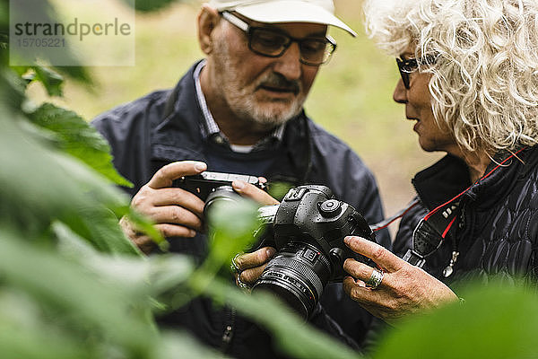 Ältere Frau spricht  während sie während eines Fotokurses einem Freund die Kamera zeigt