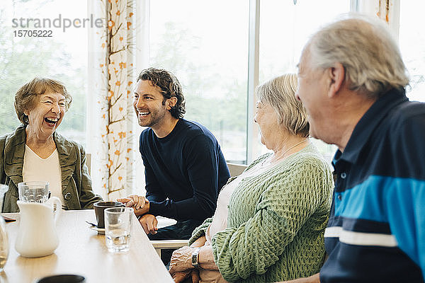 Lächelnder Mann besucht seine Großmutter und ihre Freunde im Altersheim