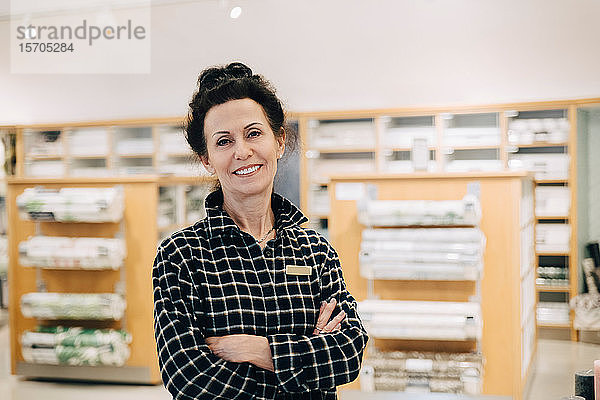Porträt einer lächelnden Verkäuferin mit verschränkten Armen im Laden stehend