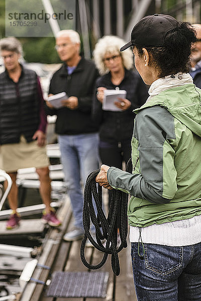 Weibliche Ausbilderin hält Seil  während sie ältere Männer und Frauen im Bootsführerkurs unterrichtet