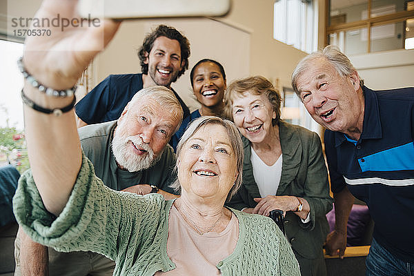 Ältere Frau nimmt sich mit Freunden und Mitarbeitern des Gesundheitswesens im Altenheim ein