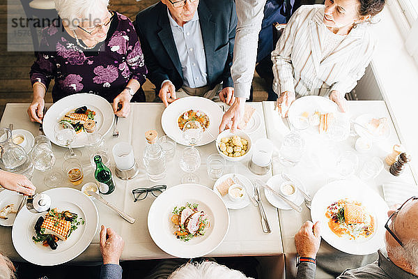 Schrägaufnahme von älteren Freunden mit Essen im Restaurant