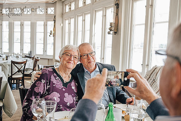 männlicher Freund klickt auf das Foto eines älteren Ehepaares im Restaurant