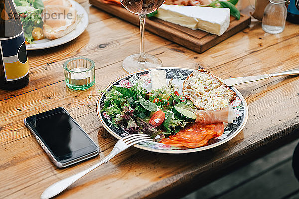 Nahaufnahme von gesundem Essen in Tellerform per Mobiltelefon auf dem Tisch während der Party