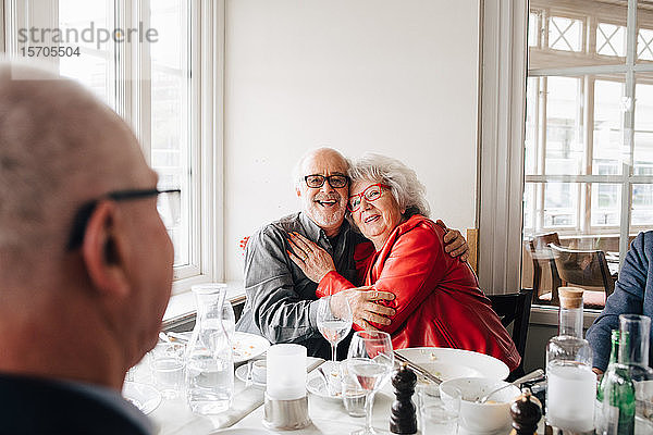 Älterer Mann umarmt Frau  während er im Restaurant sitzt