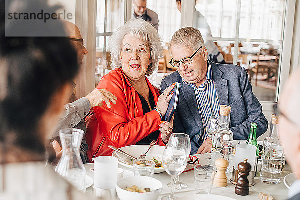 Ältere Frau versteckt Buch vor männlichem Freund  während sie im Restaurant am Tisch sitzt
