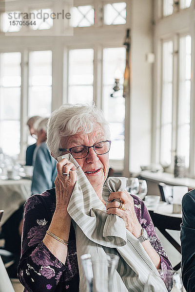 Ältere Frau weint  während sie im Restaurant sitzt