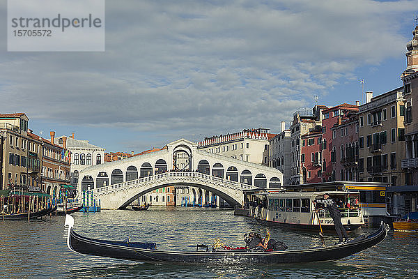 Eine Gondel überquert den Canal Grande mit einem Vaporetto und der Rialto-Brücke dahinter  Venedig  UNESCO-Weltkulturerbe  Venetien  Italien  Europa