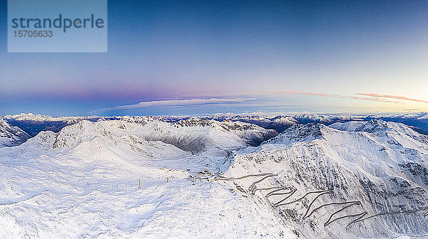 Drohnen-Panorama des Sonnenaufgangs über den engen Kurven der verschneiten Stilfserjoch-Bergstraße  Bormio  Valtellina  Lombardei  Italien  Europa