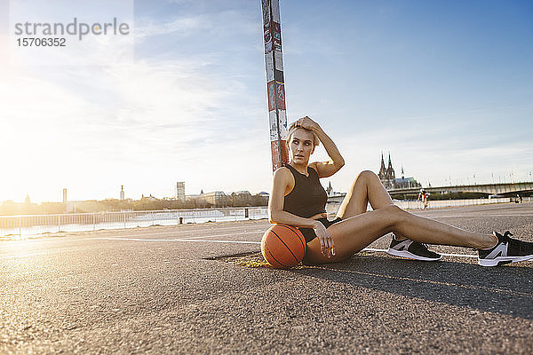 Blonde Frau sitzt mit Basketball auf einem Spielfeld in Köln  Deutschland