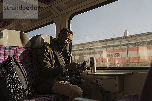 Eleganter Mann benutzt Smartphone im Zug