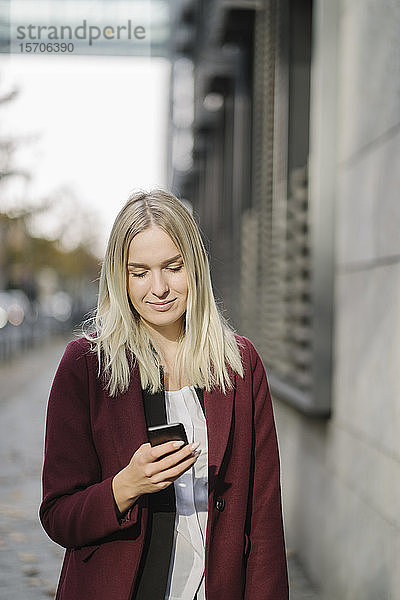Blonde Geschäftsfrau mit Smartphone in der Stadt  Blick nach unten