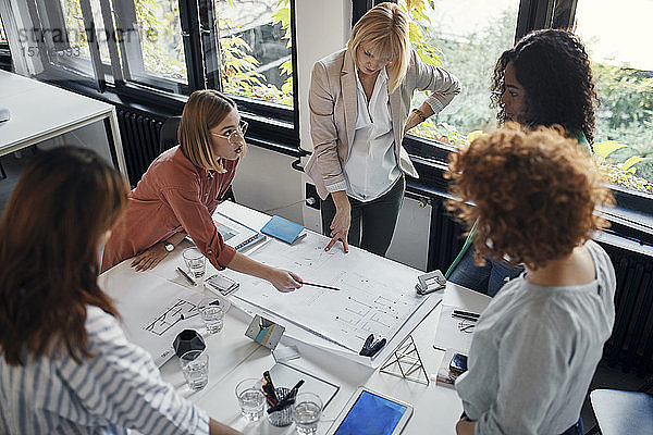 Geschäftsfrauen bei einer Besprechung im Büro mit Blaupausen auf dem Tisch