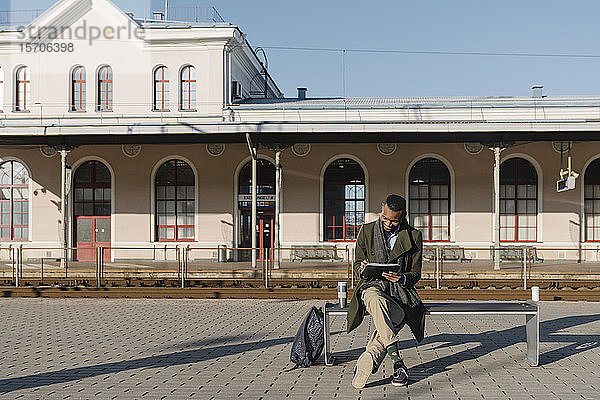 Stilvoller Mann macht sich Notizen  während er auf den Zug wartet