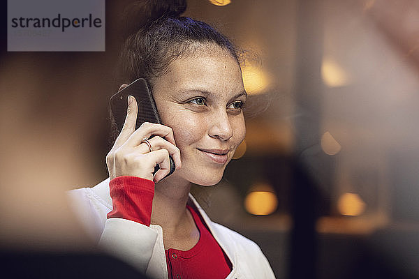 Porträt einer lächelnden jungen Frau am Telefon