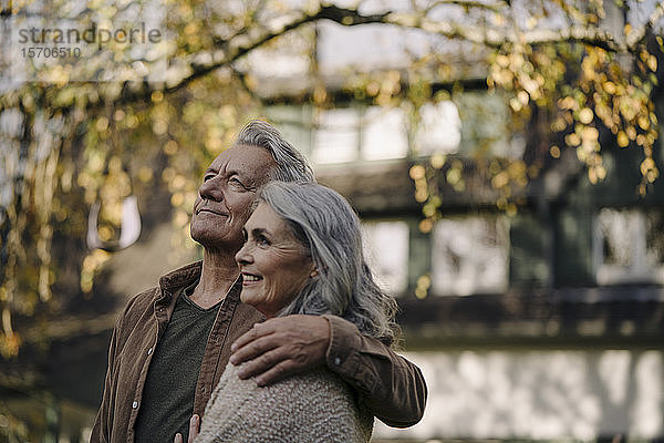Liebevolles älteres Ehepaar im Herbst im Garten ihres Hauses
