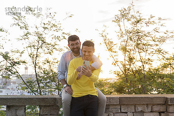 Homosexuelles Paar telefoniert bei Sonnenuntergang im Freien