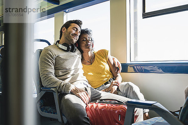 Junges Paar mit geschlossenen Augen entspannt sich in einem Zug