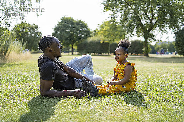 Vater und Tochter entspannen sich auf einer Wiese in einem Park