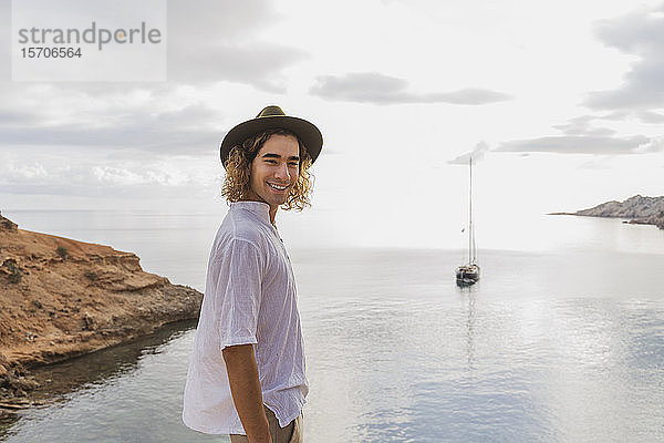 Porträt eines entspannten jungen Mannes vor dem Meer  Ibiza  Balearen  Spanien