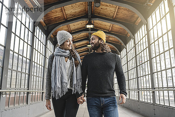Glückliches junges Paar geht Hand in Hand an einer U-Bahn-Station  Berlin  Deutschland