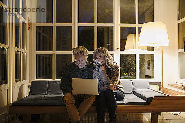 Älteres Ehepaar benutzt abends zu Hause einen Laptop auf der Couch