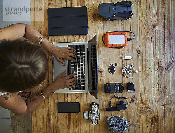 Person am Tisch sitzend mit fotografischer Ausrüstung  mit Laptop  Draufsicht