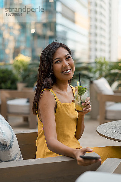 Porträt einer glücklichen Frau  die mit einem Getränk in einem Cafe sitzt
