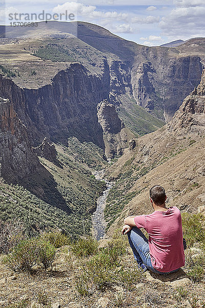 Mann sitzt auf einem Hügel an den Maletsunyane-Fällen und genießt die Aussicht  Lesotho