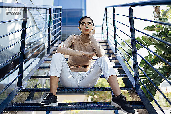 Junge Frau sitzt auf einer Außentreppe