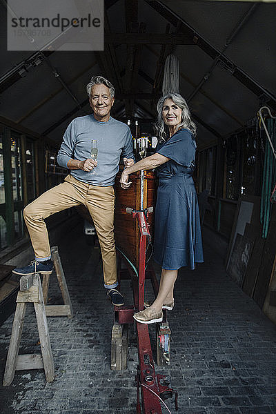 Älteres Ehepaar in einem Bootshaus mit einem Glas Champagner