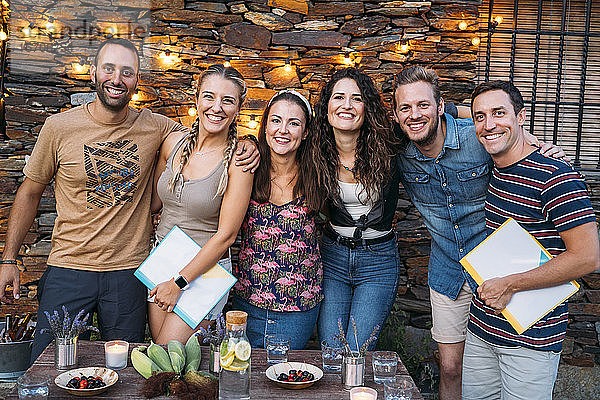 Gruppenporträt von glücklichen Freunden im Freien an einem Steinhaus