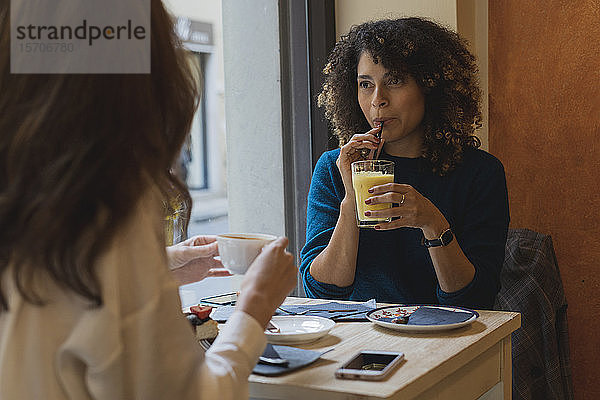 Zwei Frauen treffen sich und unterhalten sich in einem Cafe