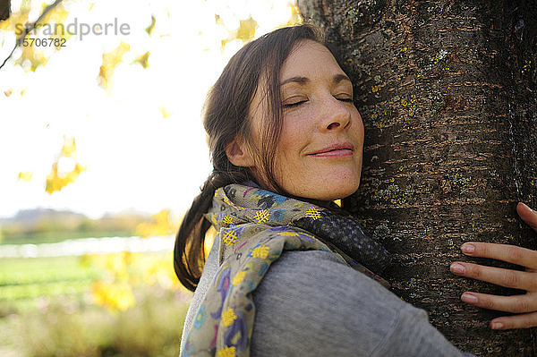 Porträt einer Frau  die einen Baum umarmt