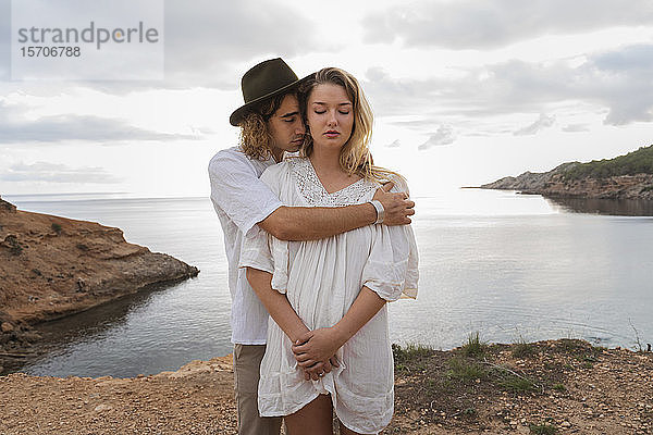 Porträt eines jungen verliebten Paares  das mit geschlossenen Augen vor dem Meer steht  Ibiza  Balearen  Spanien